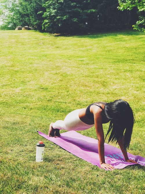 A Woman in Black Tank Top Working Out on the Grass