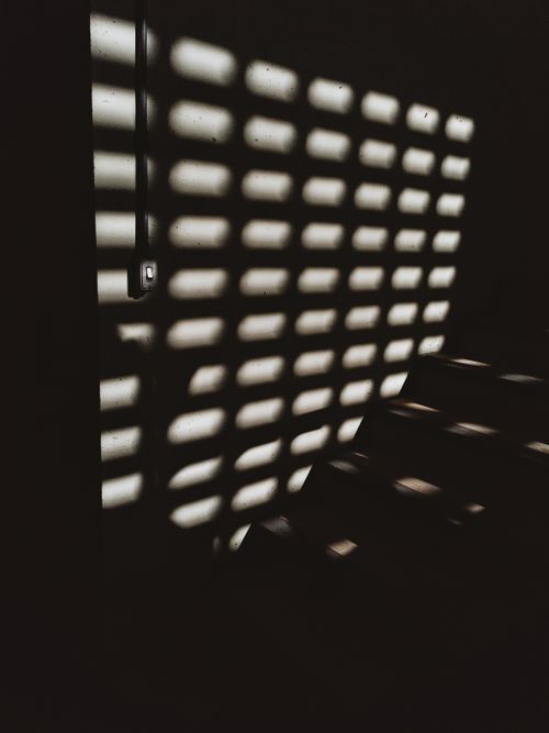 Free Artistic shadow pattern cast on concrete wall in a dimly lit stairwell, creating a dramatic effect. Stock Photo