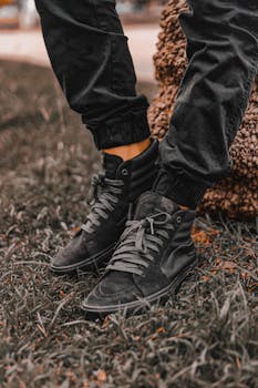 Close-up of trendy black sneakers on grass, perfect for fashion and lifestyle themes.