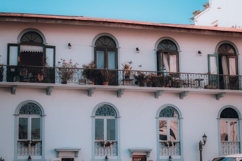 Free A beautiful exterior view of a colonial building with arched windows and a balcony adorned with plants. Stock Photo