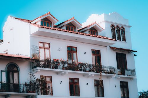 Free Charming white building with balconies and a red tile roof against a clear blue sky. Stock Photo