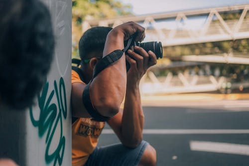 A Man in Orange Shirt Taking a Photo