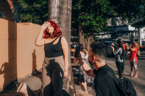 Free A woman posing playfully while a man captures the moment on a bustling street. Stock Photo
