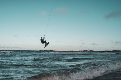 Free A dynamic shot of a kite surfer soaring above ocean waves, showcasing adventure and outdoor sports. Stock Photo