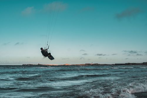 Free Kite surfer skillfully rides the ocean waves under a bright blue sky, showcasing thrilling watersport action. Stock Photo