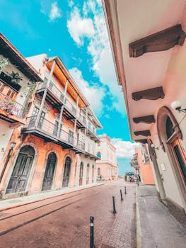 Vibrant colonial architecture on an empty cobblestone street in Casco Viejo, Panama City, under a clear blue sky.