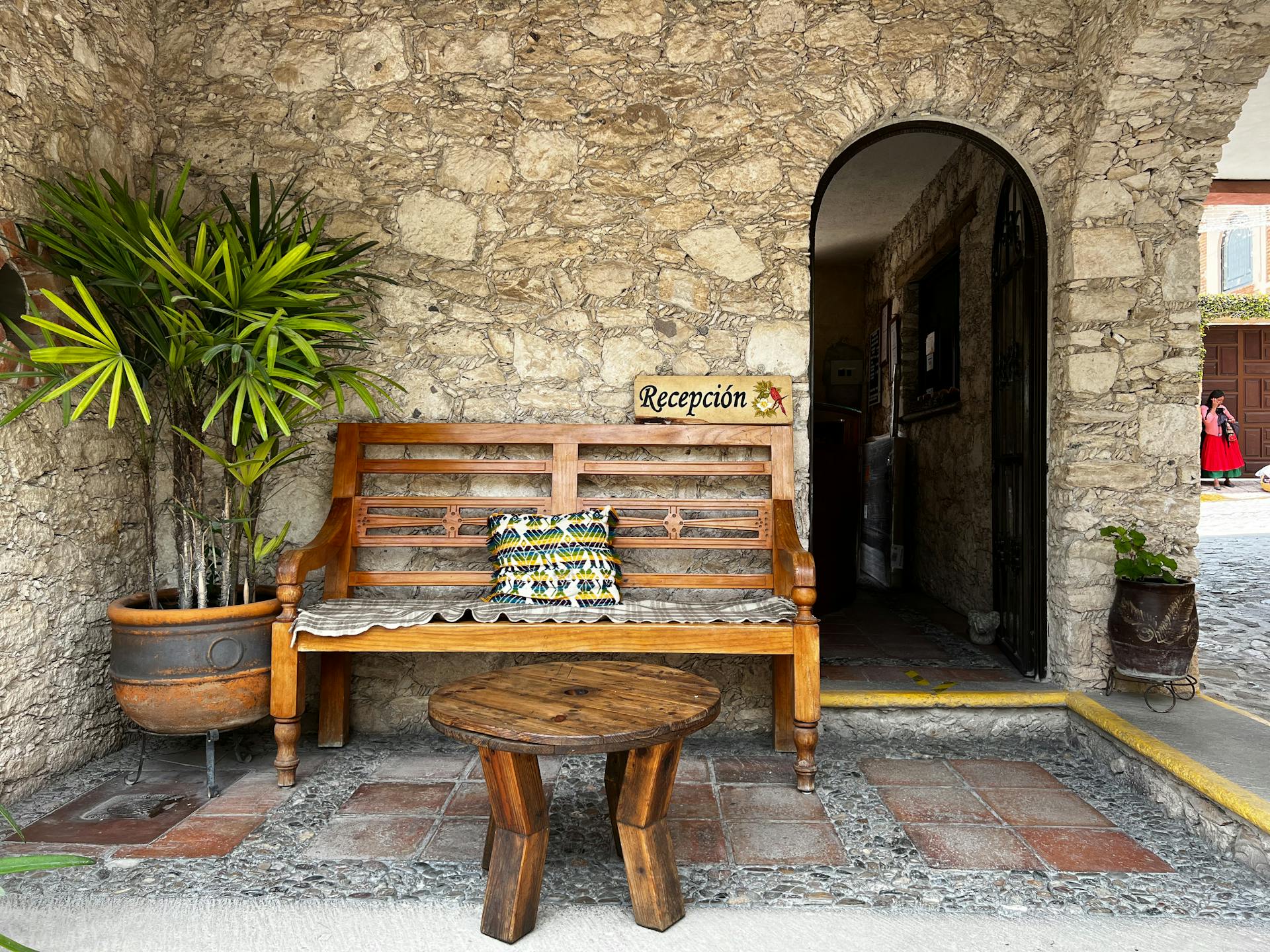 Rustic reception area with wooden bench and potted plants in Querétaro, Mexico.
