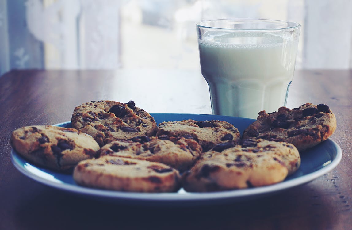 Печенье на тарелке рядом с чашкой молока