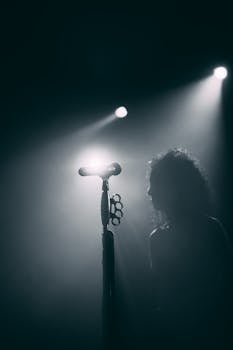 Silhouette of a performer with microphone and spotlight on stage, capturing a concert's intense atmosphere.