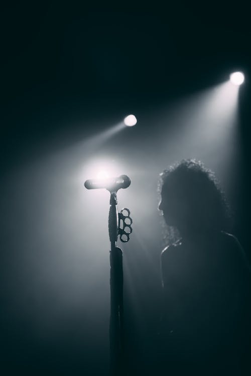 Silhouette of a Man Standing Beside the Mic Stand