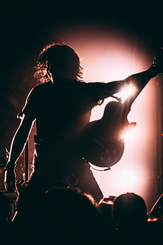Silhouette of a guitarist performing on stage with dramatic lighting creating a dynamic ambiance.