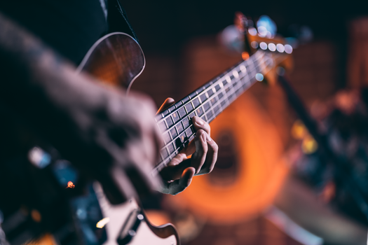 Musician's hands playing an electric guitar with a blurred background.