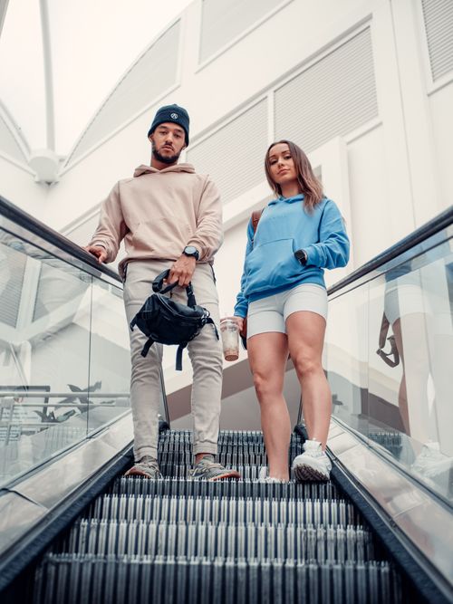Free Fashionable young man and woman posing on an escalator, showcasing modern street style. Stock Photo