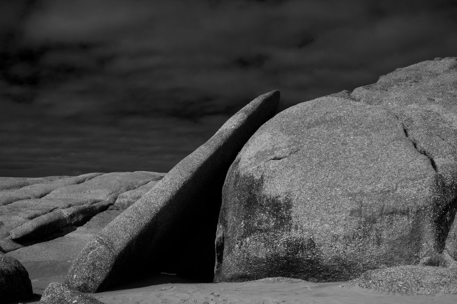 Black and white close-up of textured rocks under a moody sky, showcasing natural beauty.