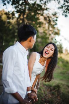 A happy couple enjoys a playful moment together amidst nature, embracing love and joy. - Fotografer Sidoarjo