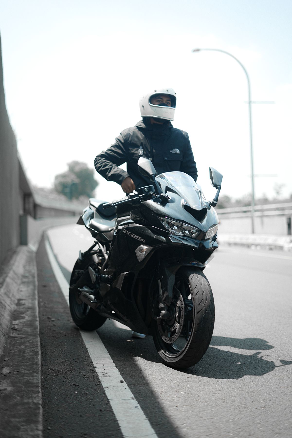 A rider in a full-face helmet sitting on a black motorcycle at the roadside