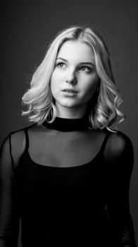 Elegant black and white portrait of a stylish young woman with curly hair