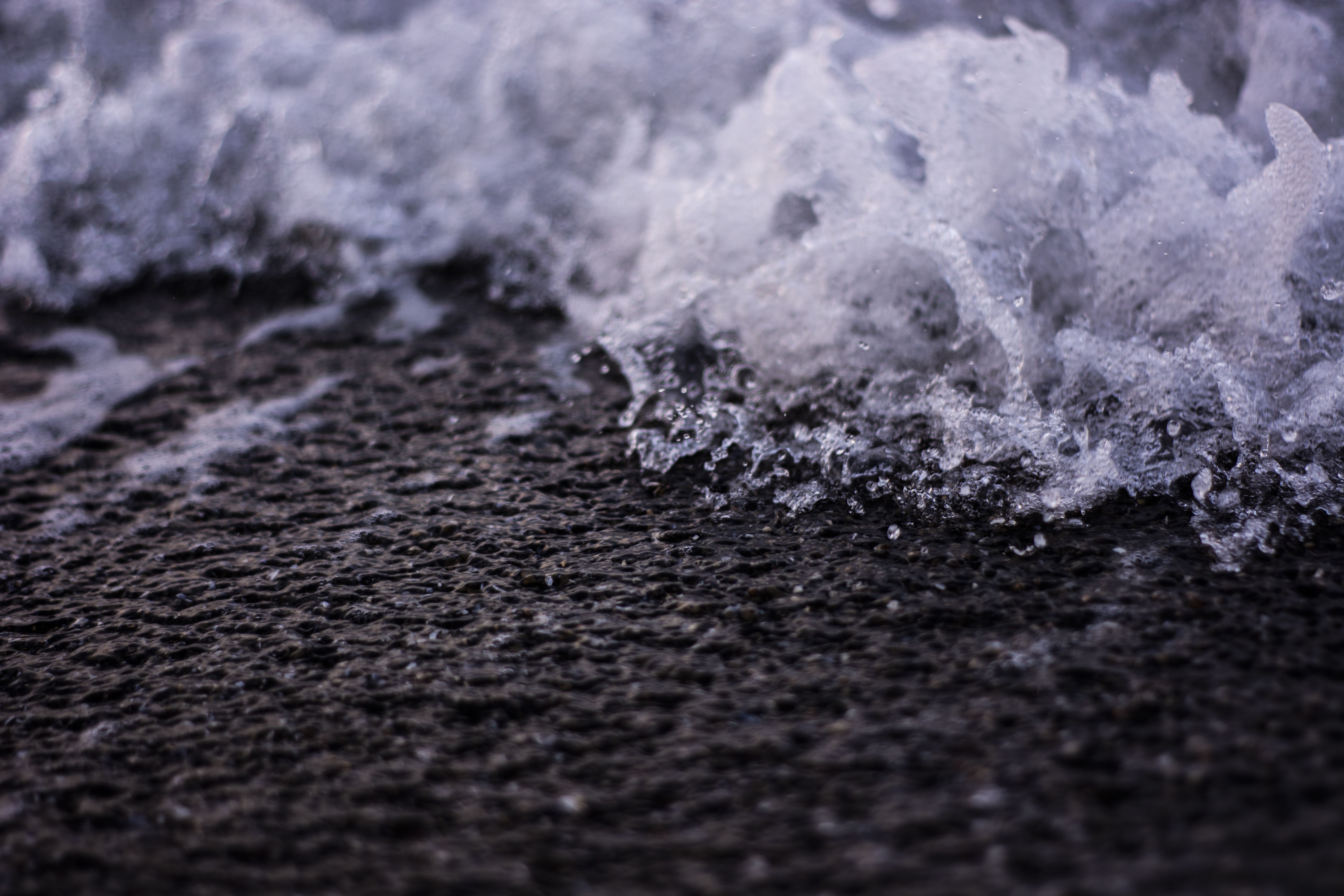 Detailed close-up of ocean waves crashing onto a rocky shore with visible water splash.