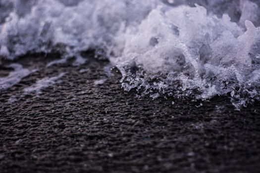 Detailed close-up of ocean waves crashing onto a rocky shore with visible water splash.