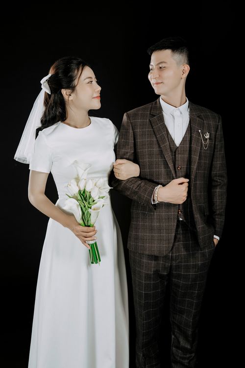 Free A captivating portrait of an Asian couple in wedding attire gazing affectionately at each other. Stock Photo