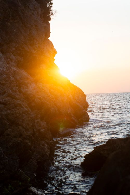 Free Sunset view over rocky cliffs and ocean, capturing the serene coastal beauty. Stock Photo