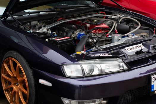 Close-up of a purple car engine featuring custom modifications and orange alloy wheels.