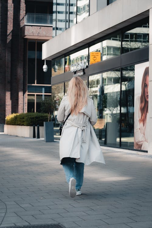 Woman in White Coat Walking on Sidewalk