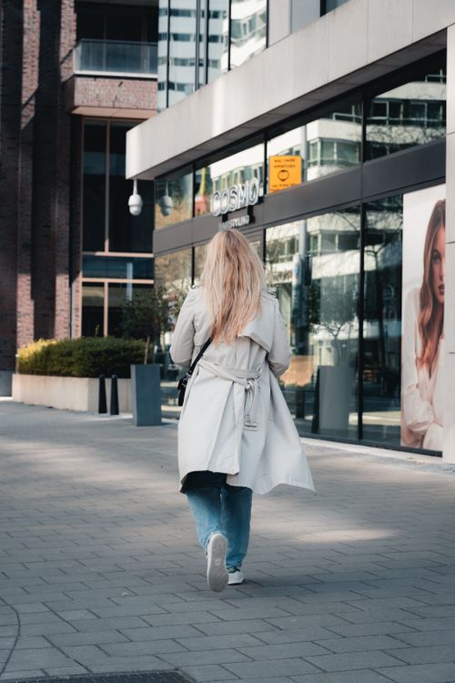 Free A woman with blonde hair walks in the city, showcasing modern architecture. Stock Photo