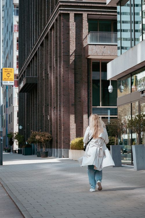 Woman in White Trench Coat Walking on Sidewalk · Free Stock Photo