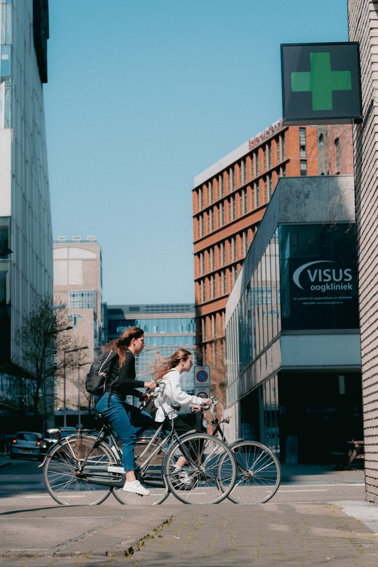 Women Riding Bikes Passing Buildings