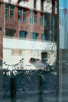 Bicycles reflected in a glass window with city architecture background.