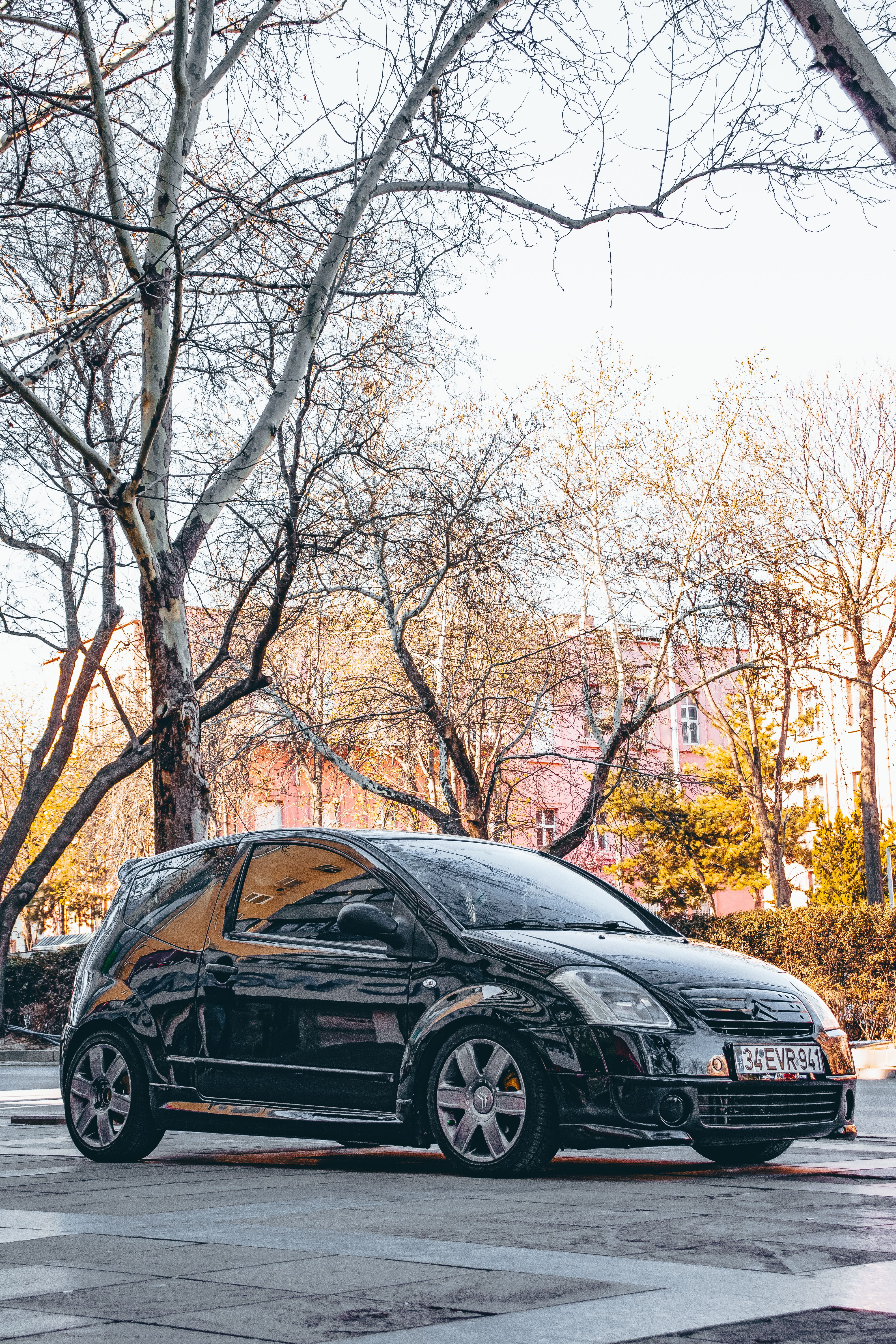 Black car reflecting in the sun, parked on an urban street in Ankara.