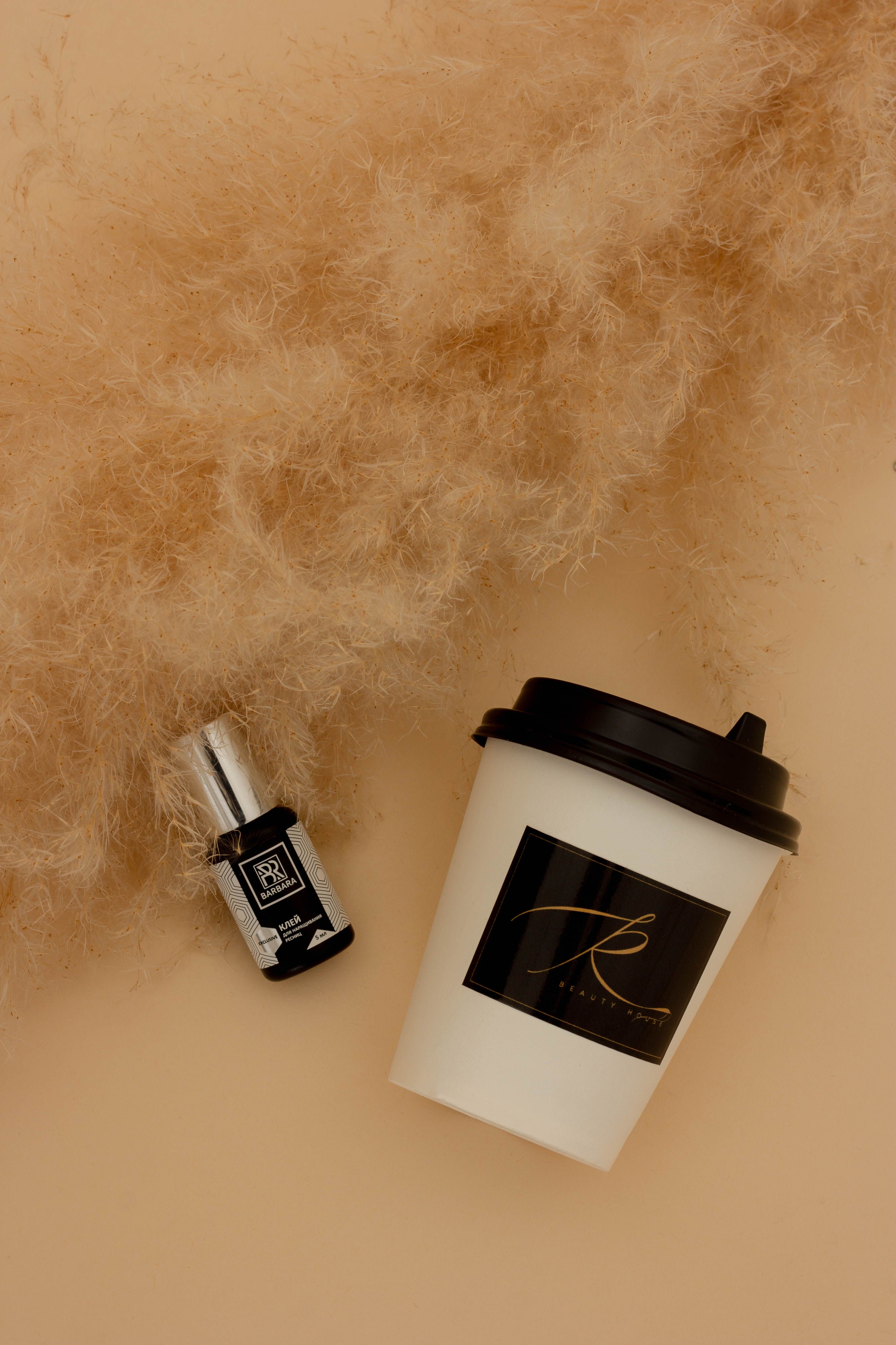 Stylish product display featuring a disposable coffee cup and accessory on a beige surface.