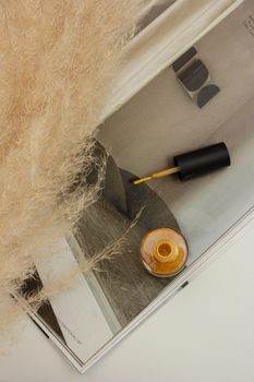 Flat lay of nail polish bottle with open brush on a fashion magazine, showcasing modern elegance.