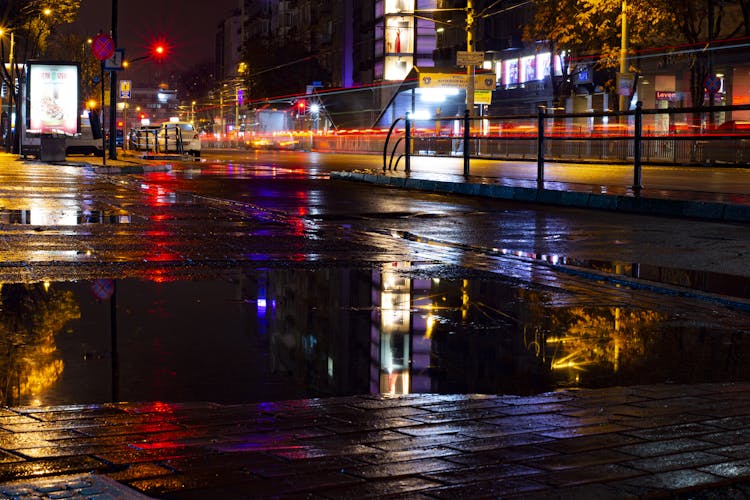 City Street In Rain With Puddle On Pavement