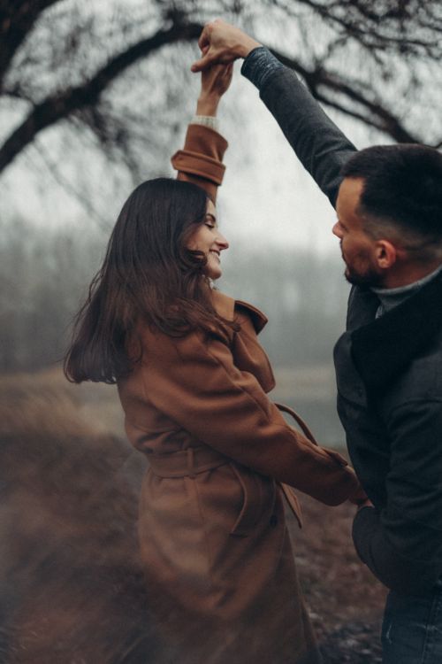 Free A happy couple dances in a foggy autumn park, surrounded by nature. Captured in warm, earthy tones. Stock Photo