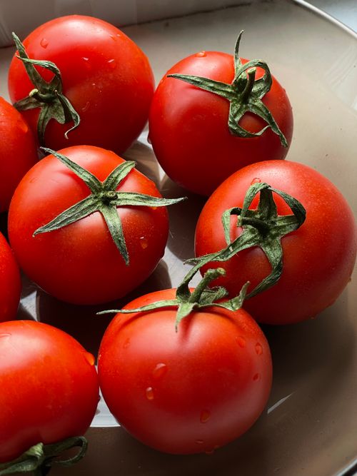 Free A close-up view of fresh ripe tomatoes with water droplets, showcasing their vibrant red color. Stock Photo
