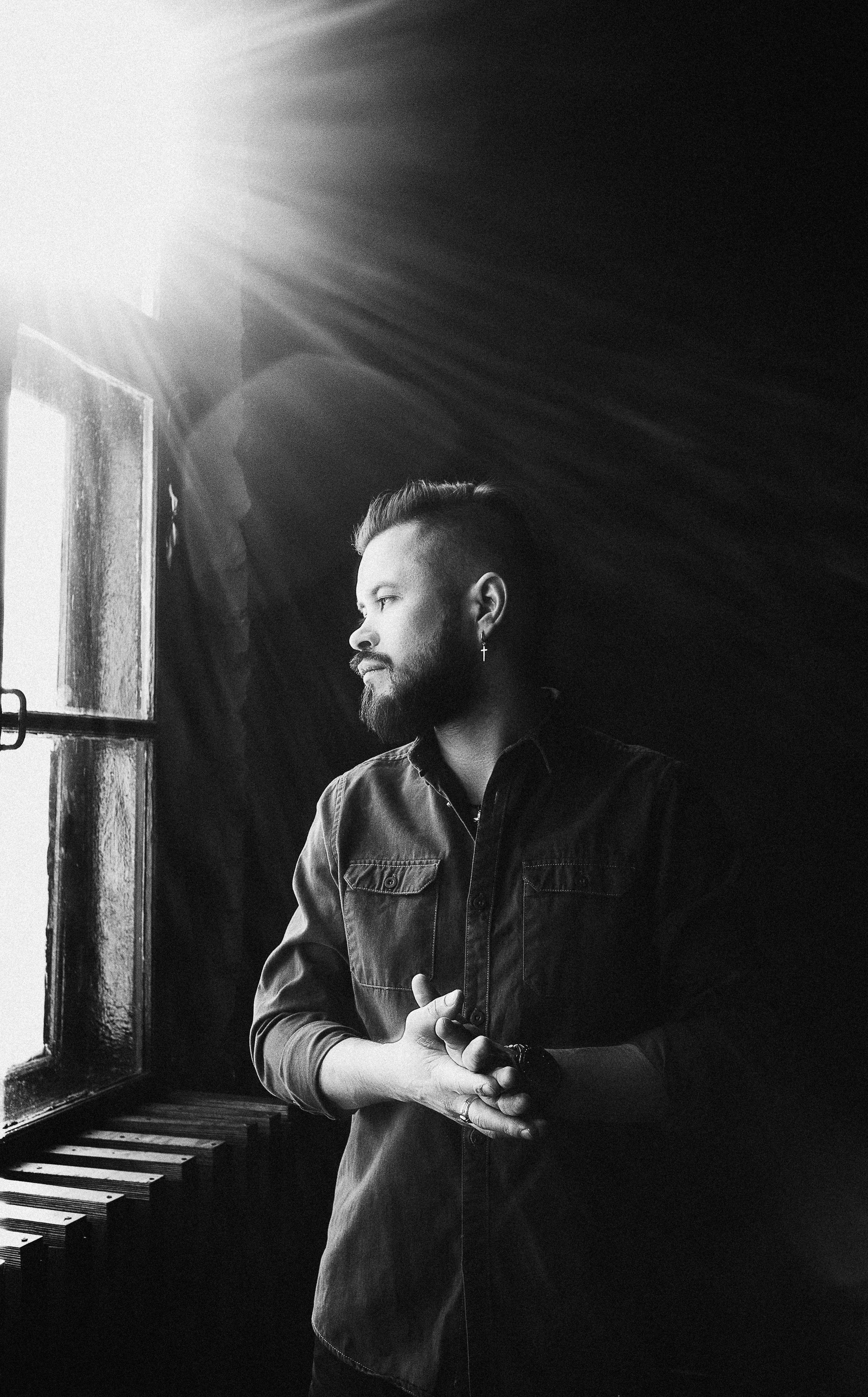 A monochrome photo of a man looking out a window, captured in a serene moment.