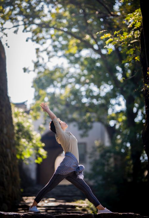 Free A woman stretching in a yoga pose outdoors amidst lush greenery, emphasizing health and fitness. Stock Photo