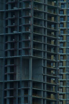 Modern high-rise building under construction, showcasing intricate architectural design at dusk.