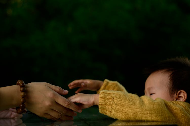 Child Reaching Out To A Person's Hand