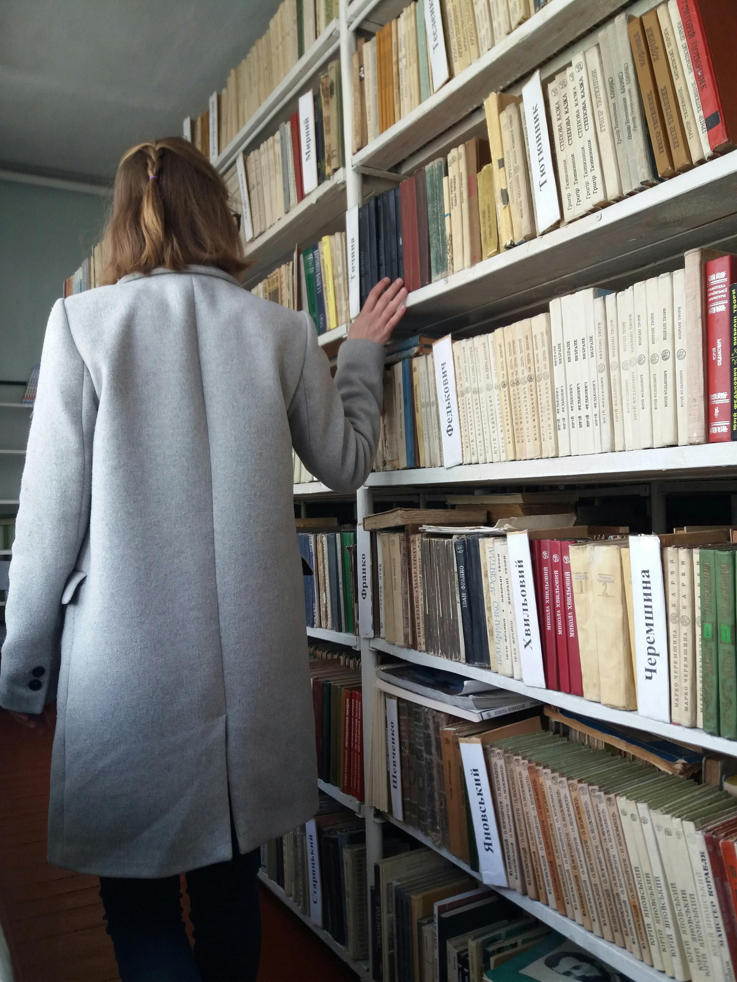 back view of a person in gray coat looking for books
