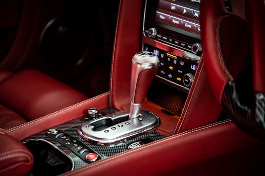 Close-up of a luxury car's interior featuring a gearstick and sleek red leather seats.
