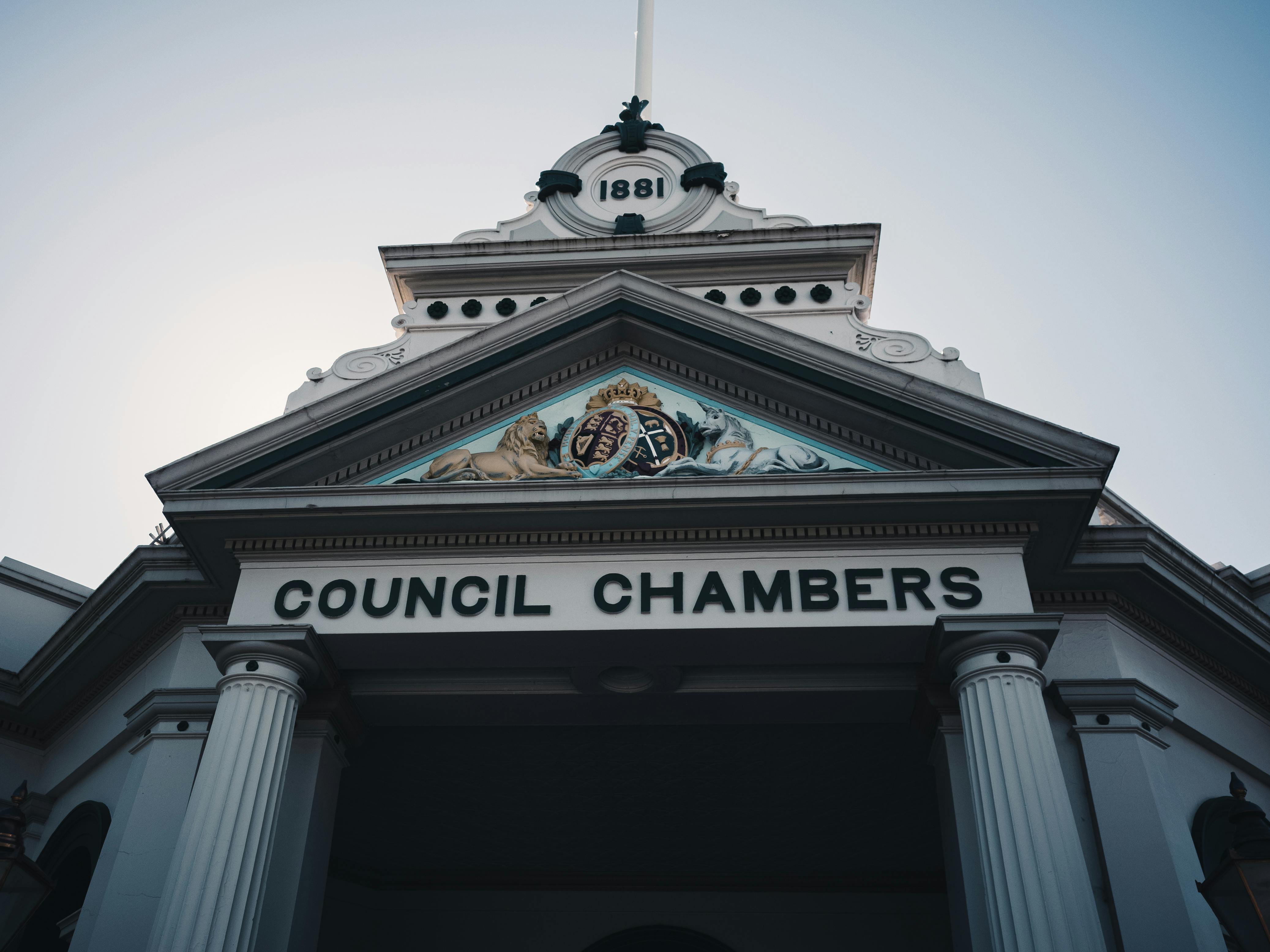 Low angle view of a historic neoclassical council chambers facade with columns and ornate detailing.