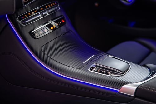 Free Close-up view of a luxury car's console with illuminated control buttons and carbon fiber finish. Stock Photo