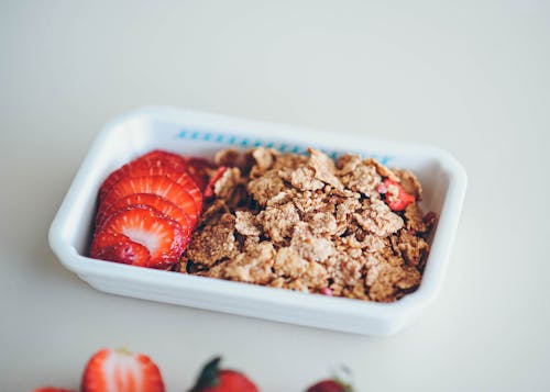 Slices of Strawberry and Cereals in White Plastic Container