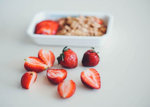Close-up of sliced strawberries with granola in a white dish, showcasing healthy and fresh food.
