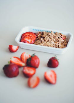 A white bowl filled with nutritious cereals and fresh strawberries perfect for a healthy breakfast.