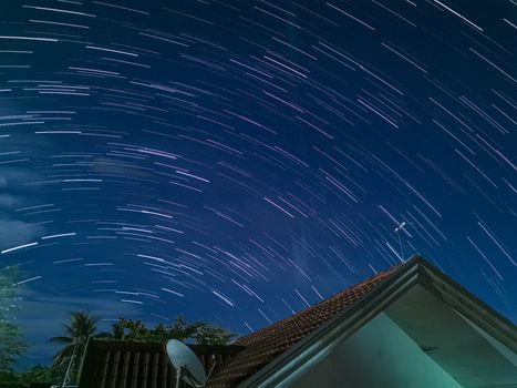 Stunning star trails photograph over a roof in Tagum City, displaying a vibrant night sky.