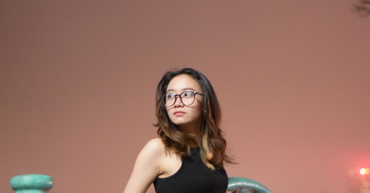 Woman in Black Tank Top with Eyeglasses Leaning on a Metal Railing ...
